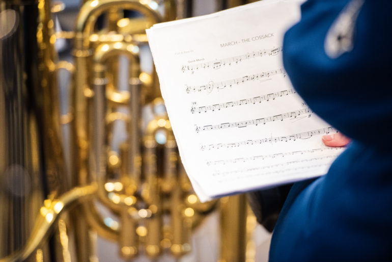 En tuba i bakgrunnen med noter og blå uniform i forkant